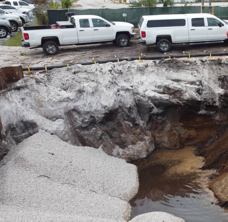 Large hole showing backfill and contamination in the soil