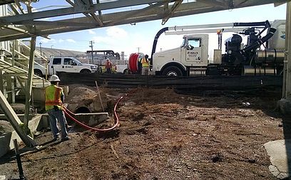 Crews working with a vacuum combination unit to clear a line using water and suction